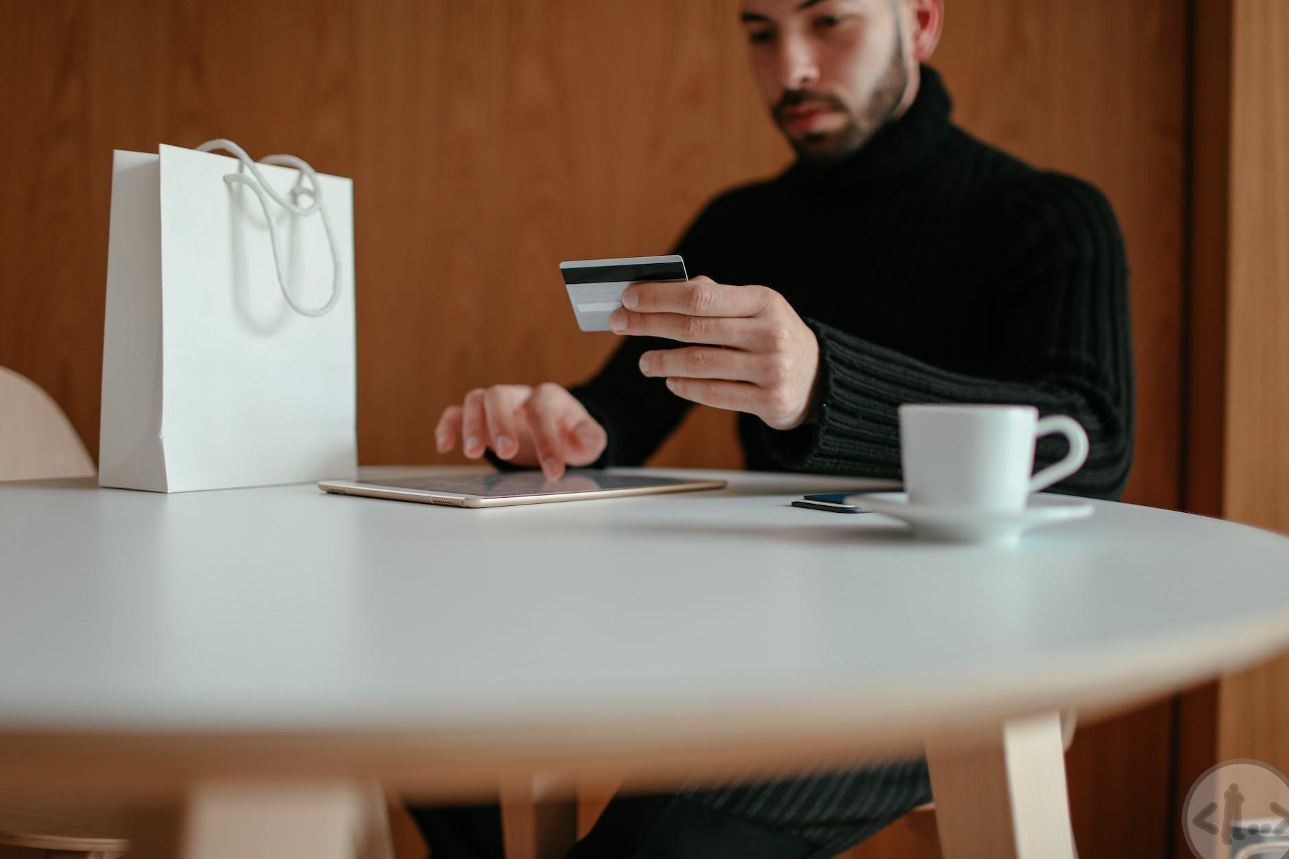stylish young male doing online shopping with tablet and credit card in cafe