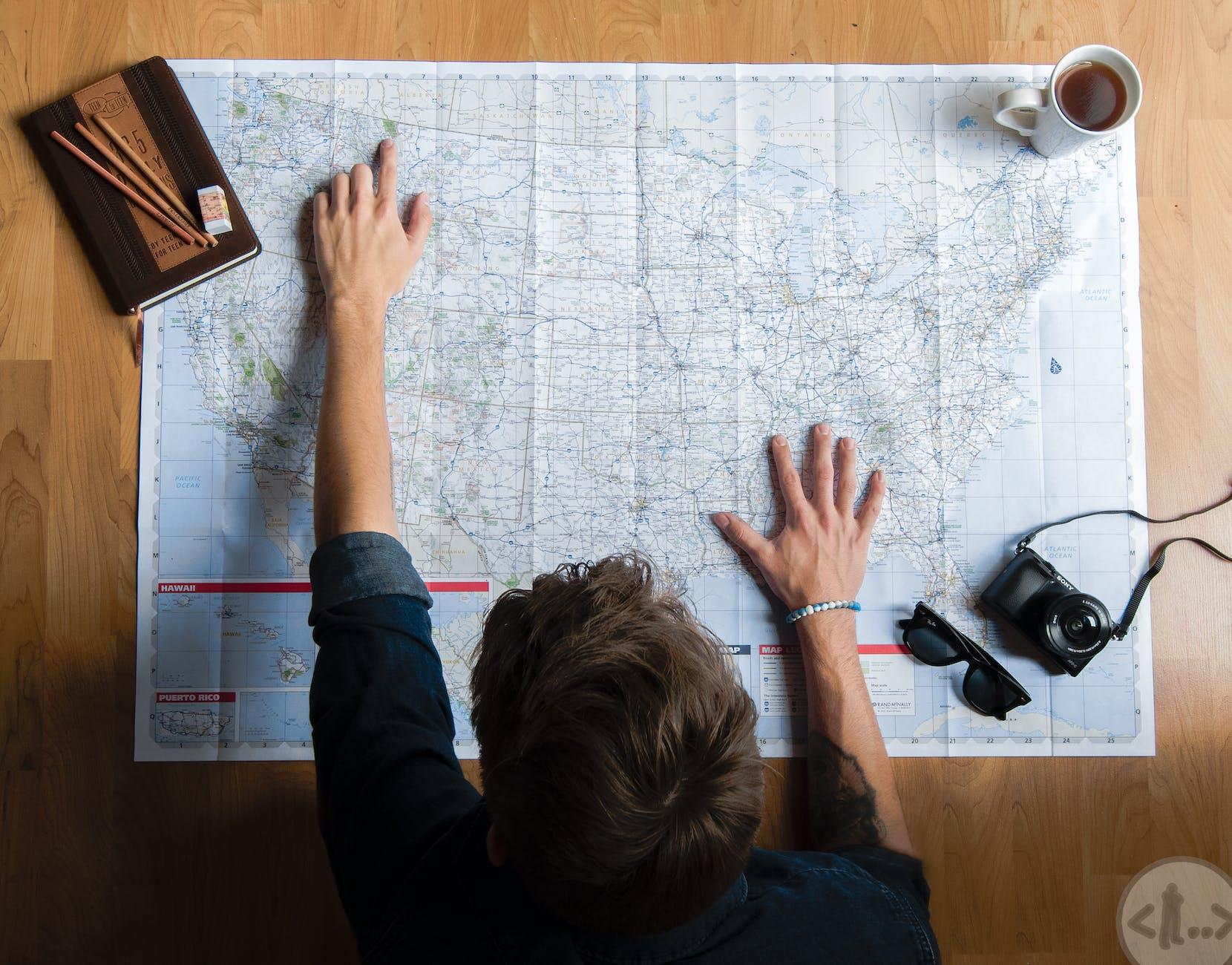 unrecognizable man examining map while planning travel at home