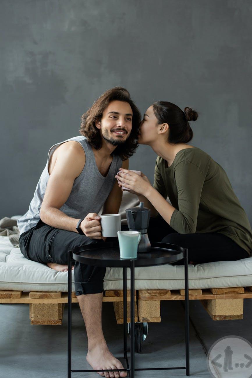 woman in green top whispering to a man in a gray tank top