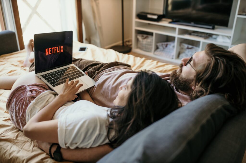 man and woman lying on bed using laptop computer
