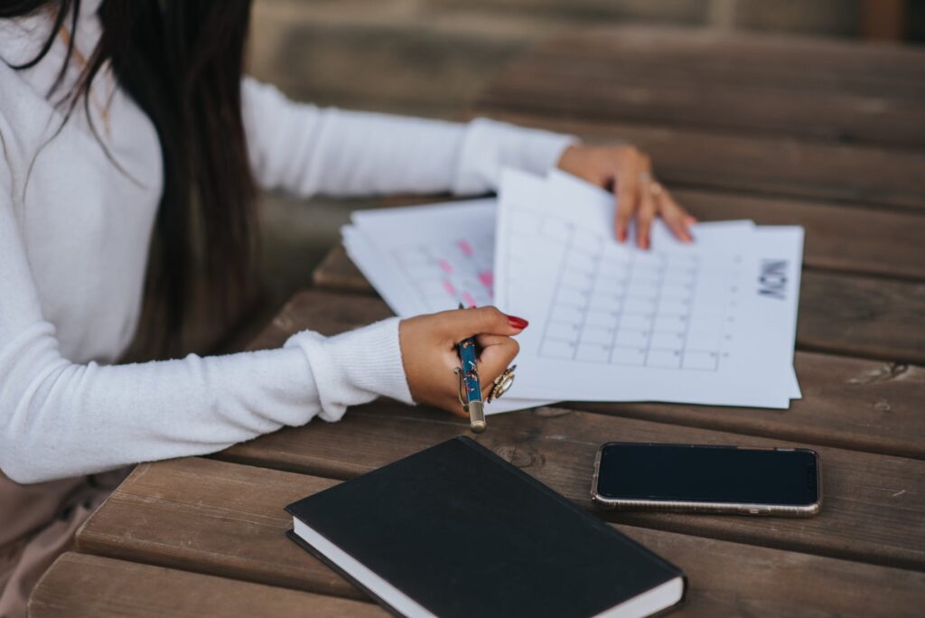 faceless ethnic worker making schedule at wooden table