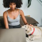 crop black woman with laptop and dog