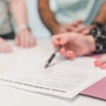 a person holding a ballpen on a white paper