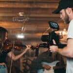 man holding camera and woman playing violin