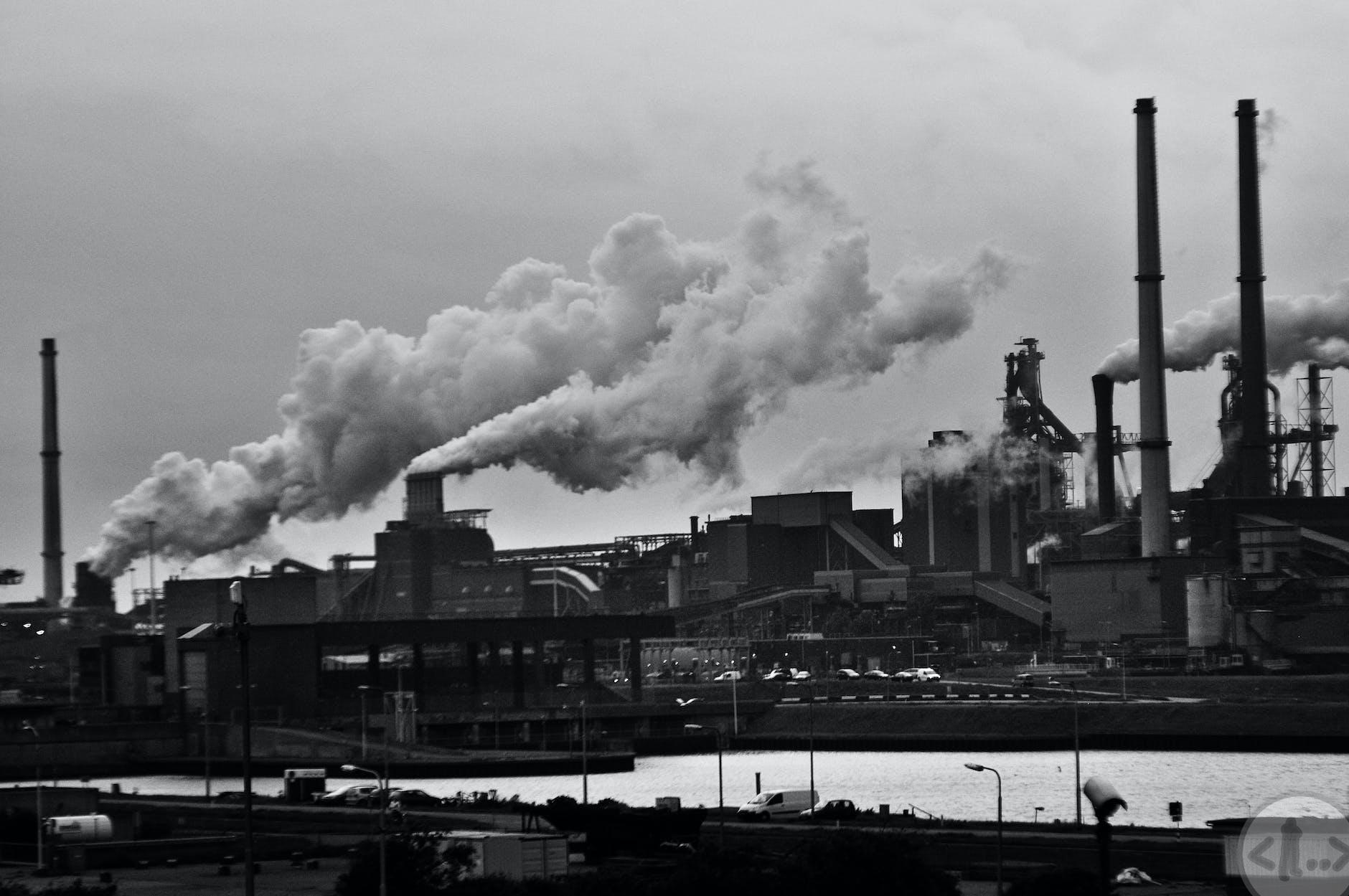 grayscale photography of locomotive train beside factory