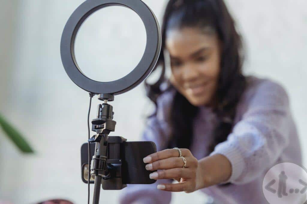 happy young black woman setting up smartphone before shooting podcast