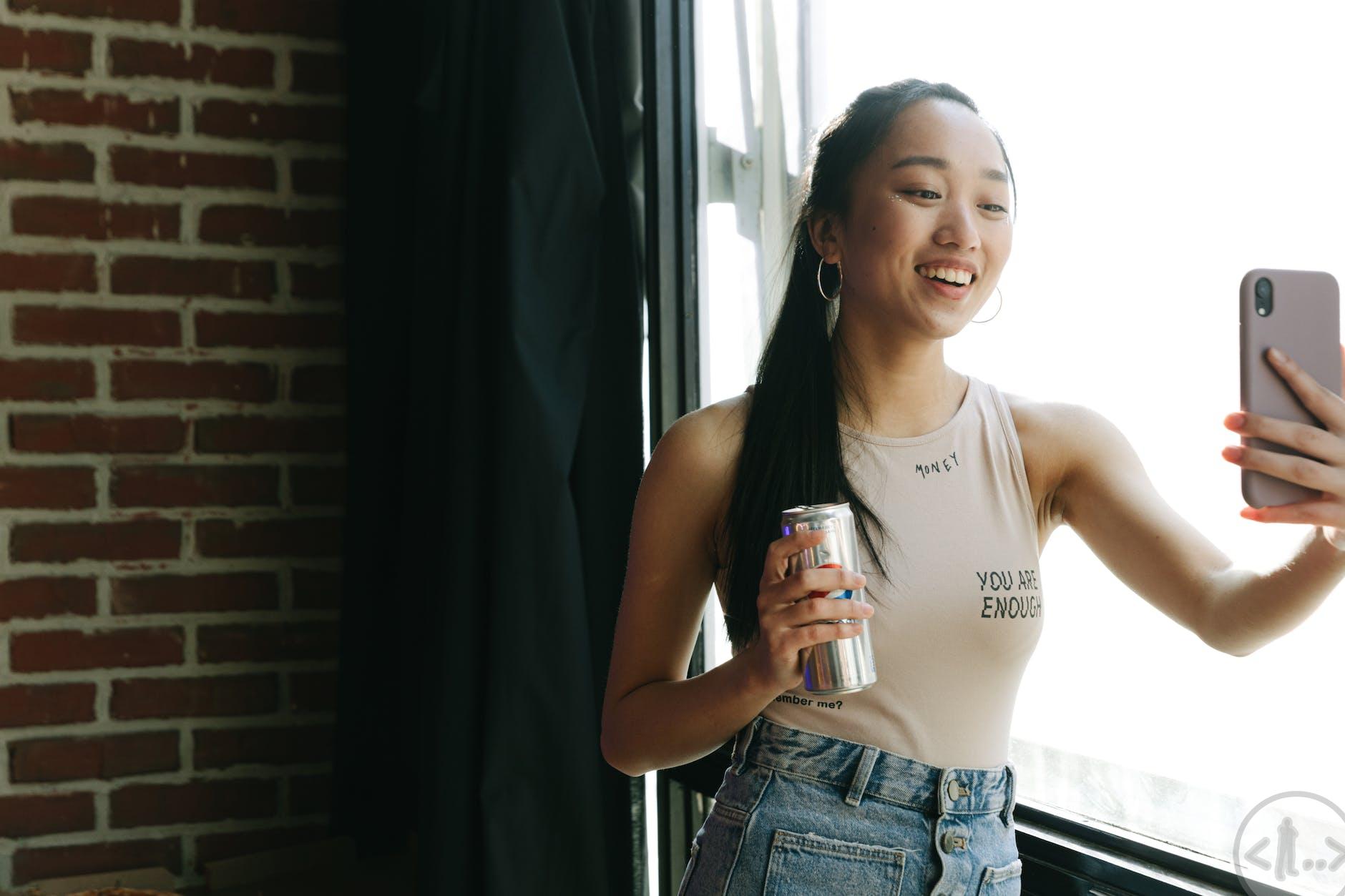 a vlogger in a tank top using her smartphone