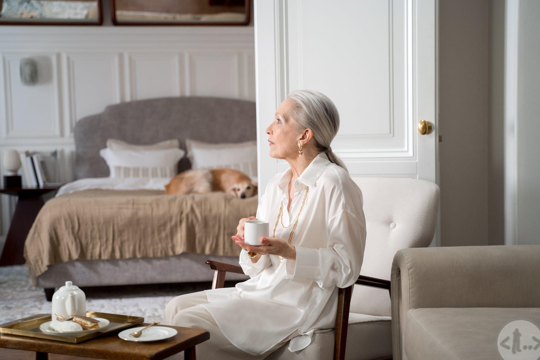 elderly woman sitting in chair and having coffee in her living room