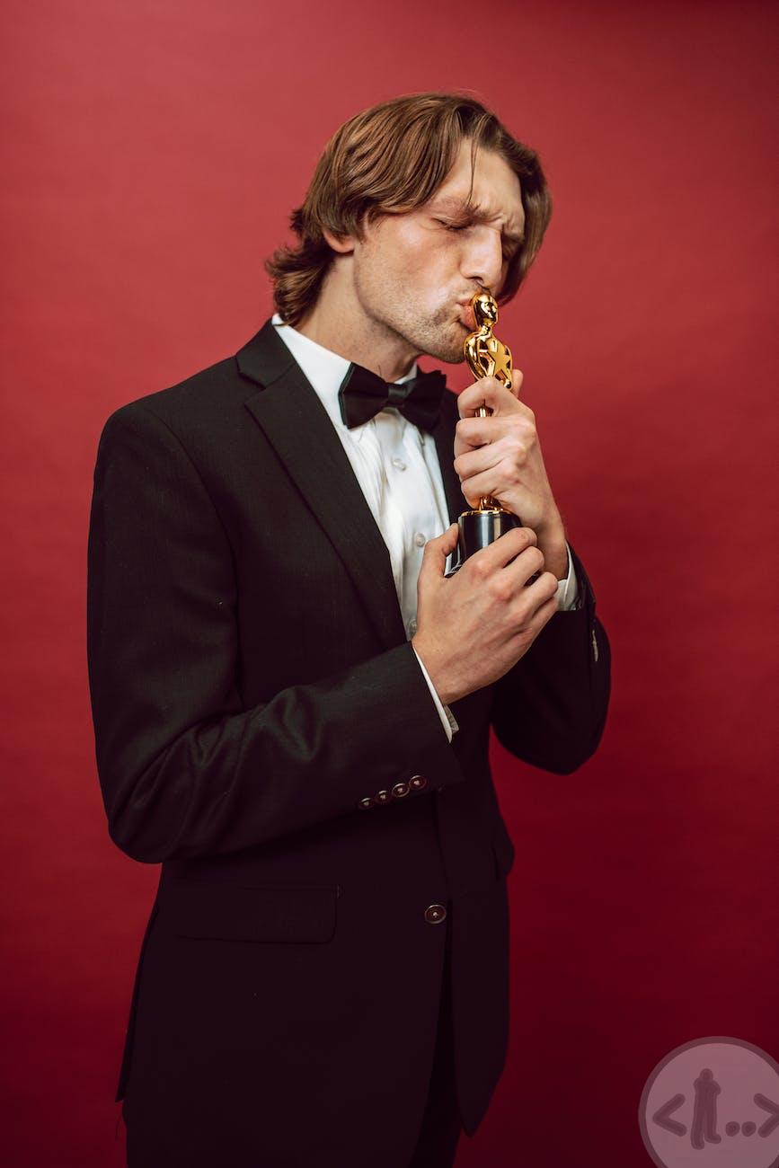 a man in a suit kissing an oscar