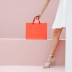 crop unrecognizable woman carrying red shopping bag in studio