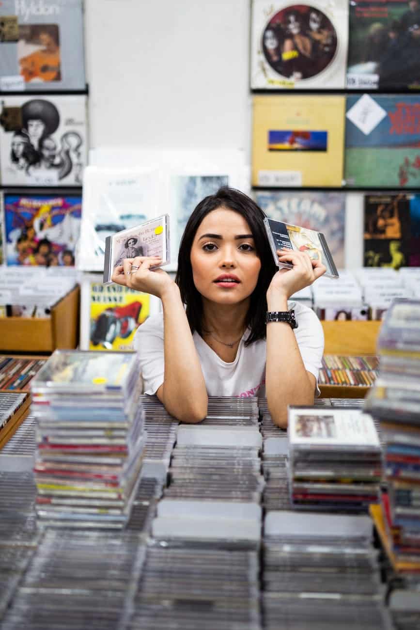 photo of woman leaning on compact disc cases